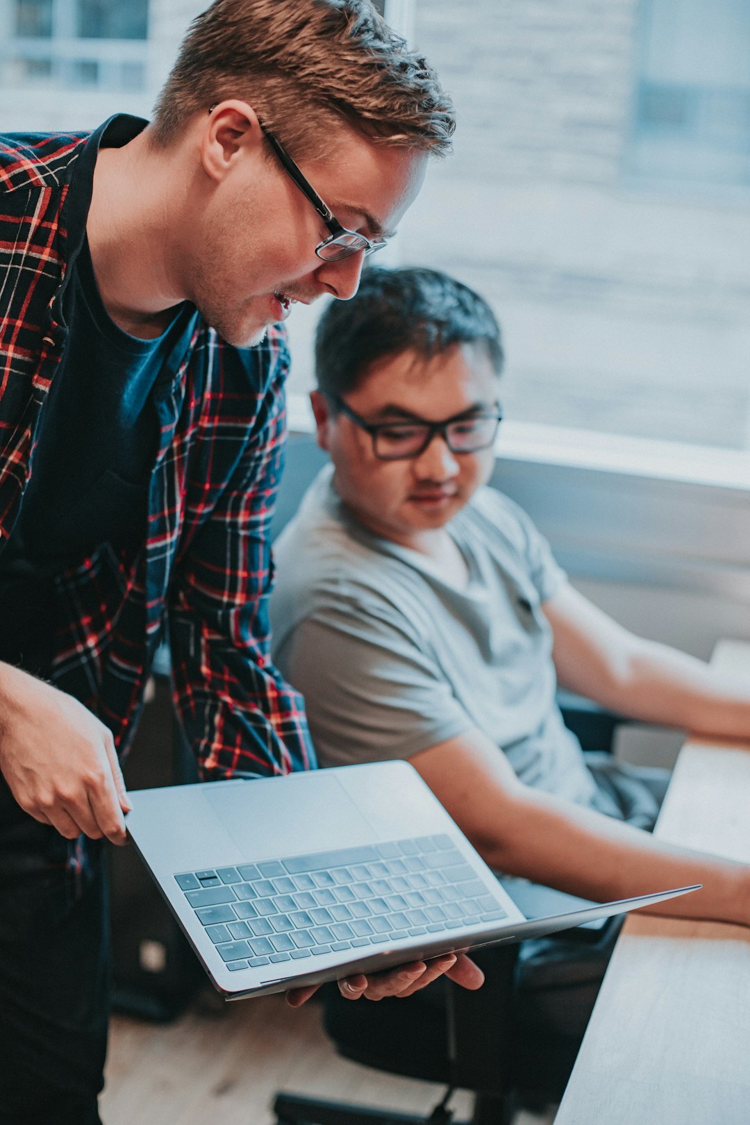 Mentor helping a student review code on a laptop